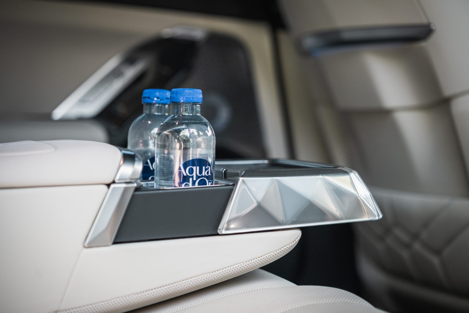Chauffeur service Düsseldorf: two bottles of water in the centre console in the back of a BMW 7 Series, light leather seats