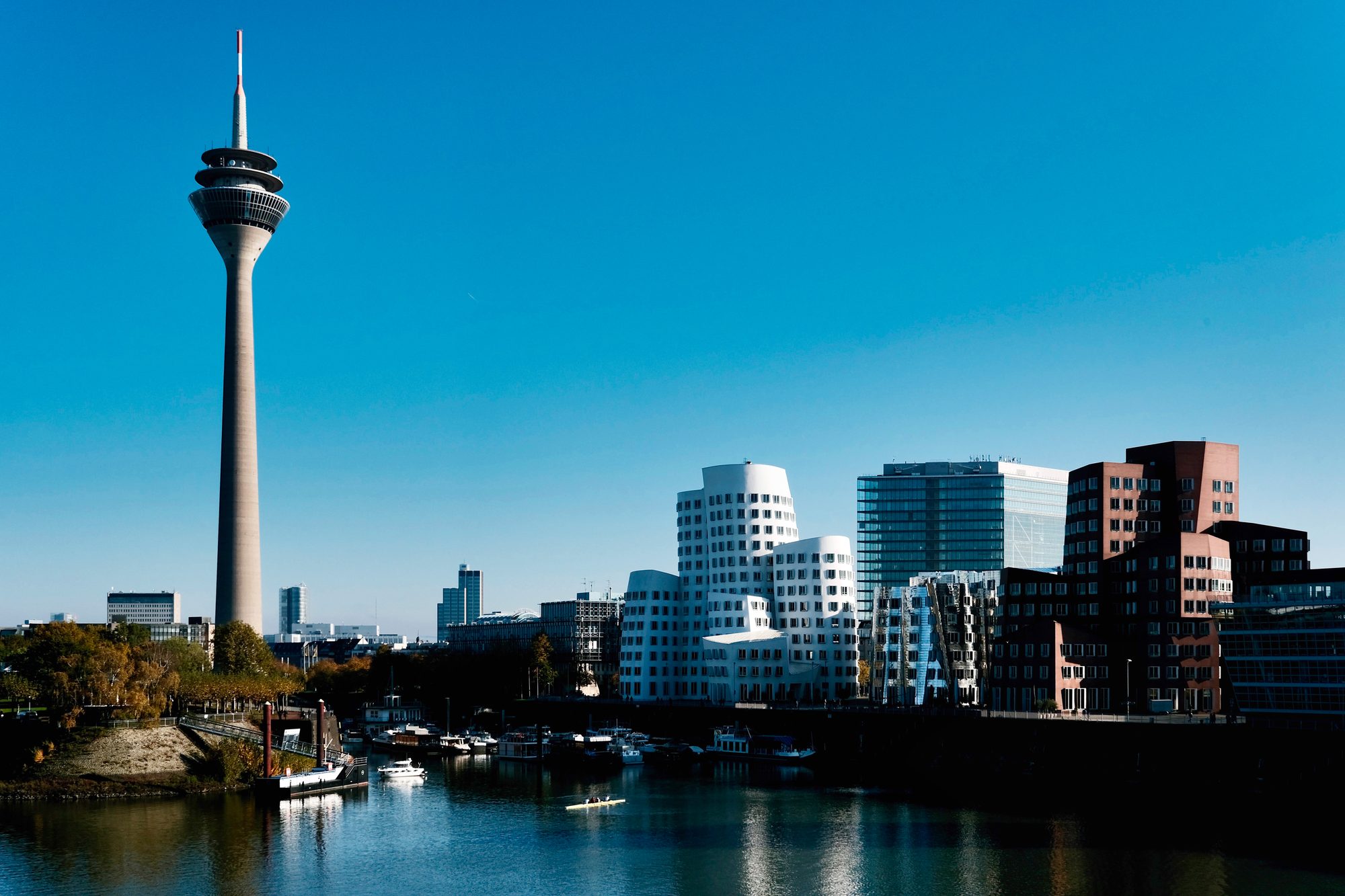 Düsseldorf's MedienHafen with the Rheinturm and the Gehry buildings on the water under a blue sky