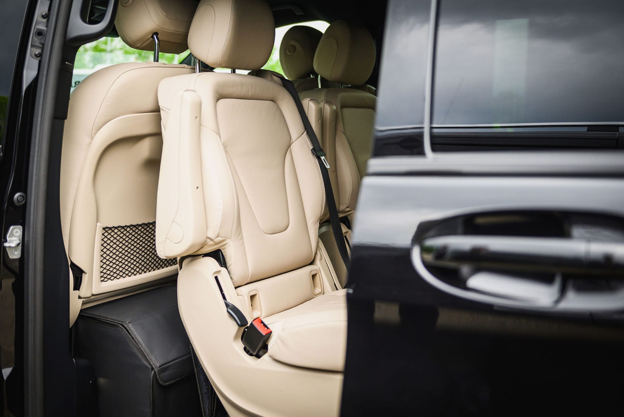 Chauffeurservice Frankfurt: Blick durch die geöffnete Schiebetür in den Fond einer schwarzen Mercedes-Benz V-Klasse mit Einzelsitzen aus hellem Leder