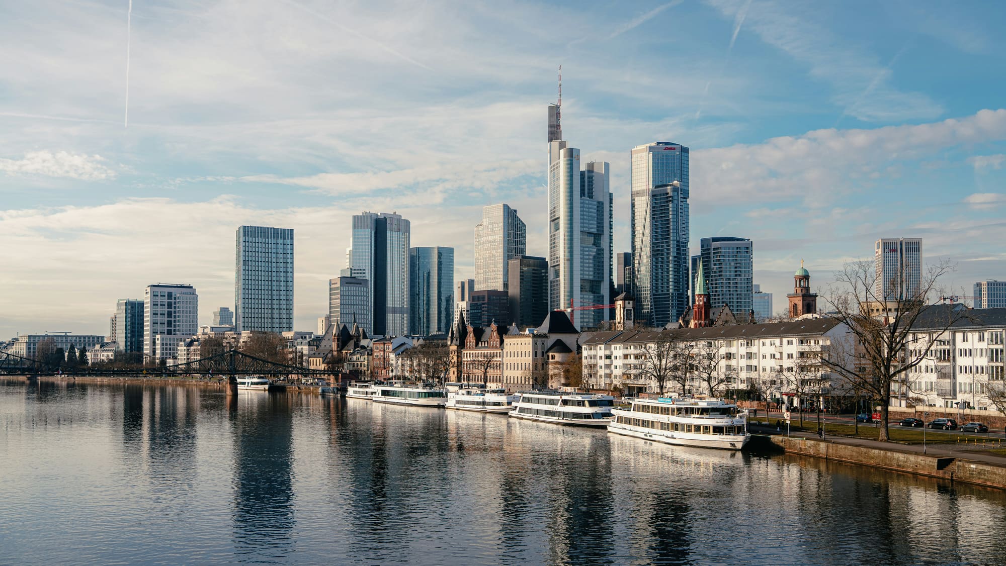 Frankfurter Skyline mit den Hochhäusern des Bankenviertels über dem Main, am Ufer liegen Ausflugsschiffe