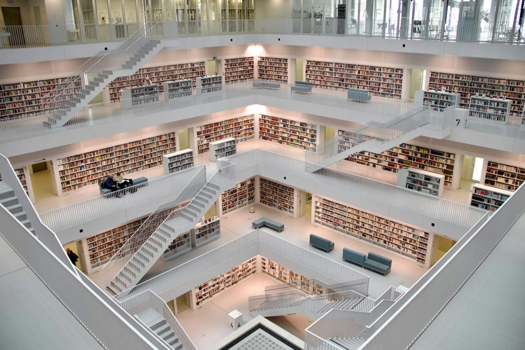 Blick von oben in den weißen Lesesaal der Stadtbibliothek Stuttgart mit Galerien, Treppen und Bücherregalen über mehrere Etagen