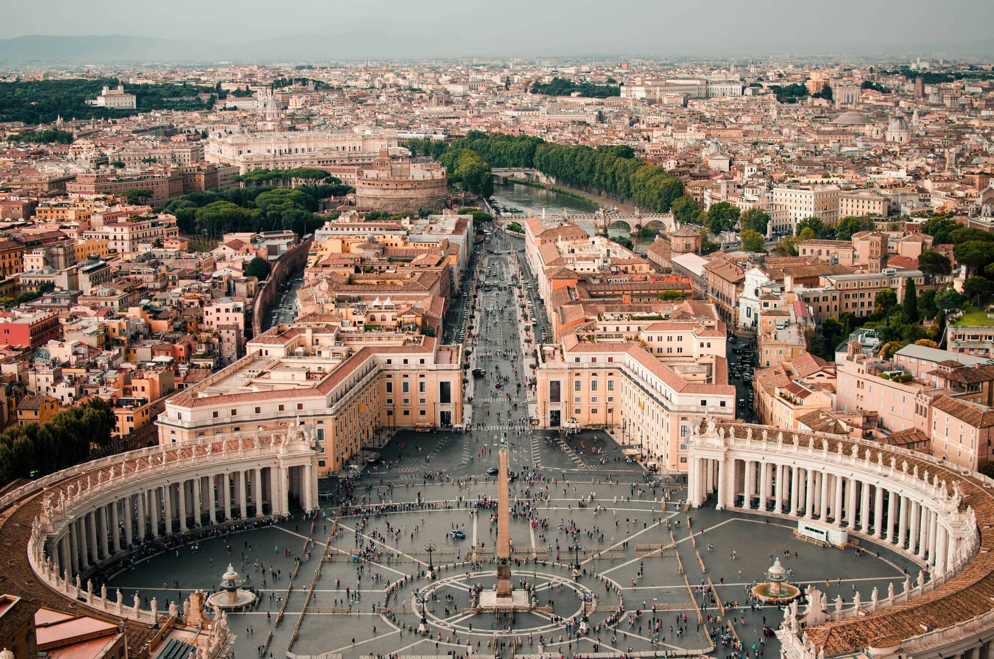 Blick von der Kuppel des Petersdoms auf den Petersplatz mit Kolonnaden und Obelisk, die Via della Conciliazione, die Engelsburg und den Tiber