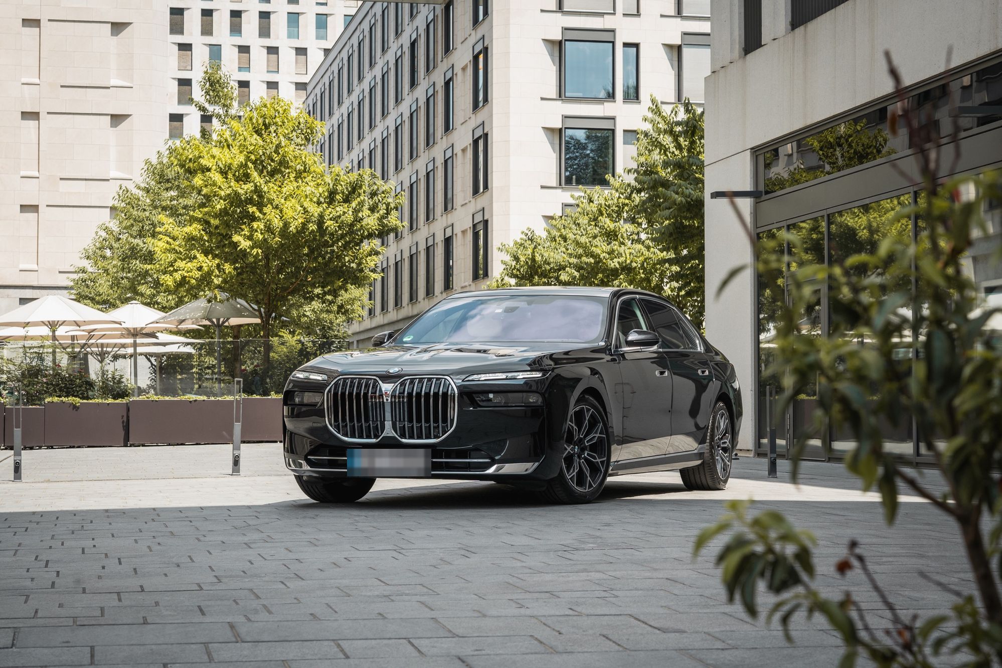 Schwarzer BMW 7er von AYDEN vor modernen Bürogebäuden
