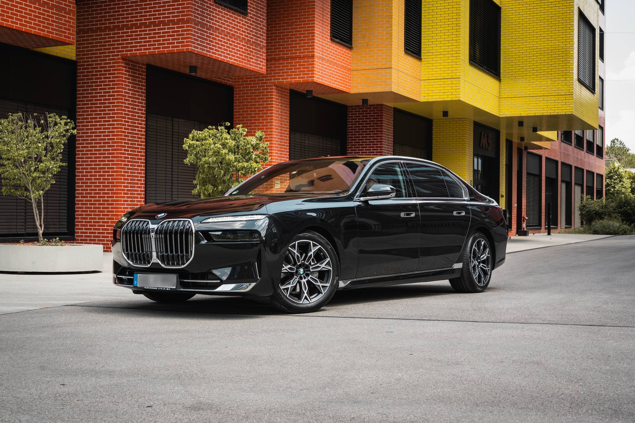 Schwarzer BMW 7er von AYDEN vor einem Bürogebäude mit Klinkerfassade