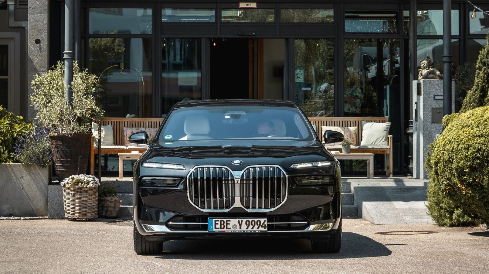 Black AYDEN BMW 7 Series with chauffeur in front of a hotel entrance