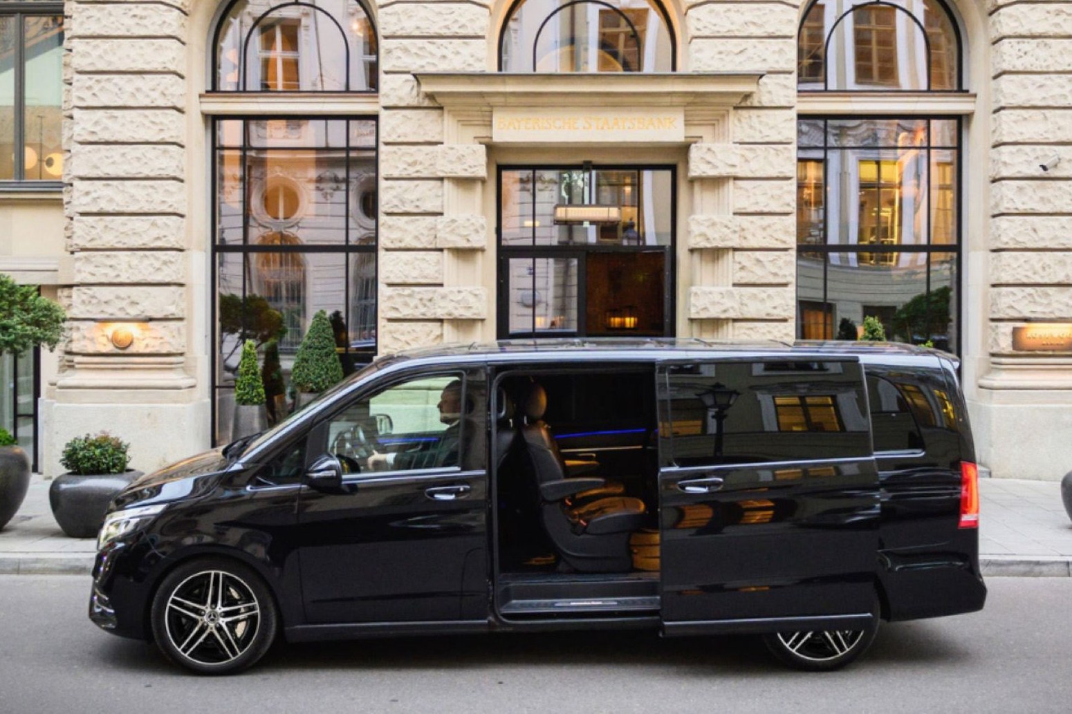 Schwarze Mercedes-Benz V-Klasse mit Chauffeur vor einem Hotel