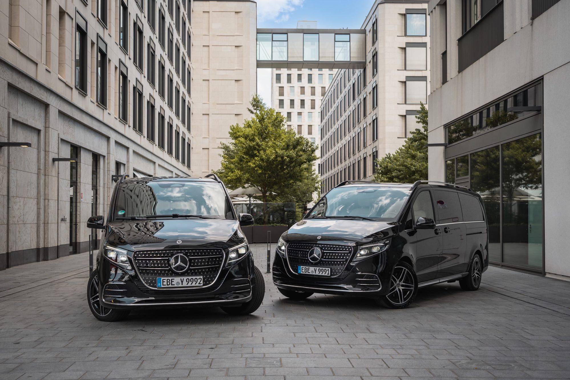 Zwei schwarze Mercedes-Benz V-Klassen von AYDEN zwischen Bürogebäuden